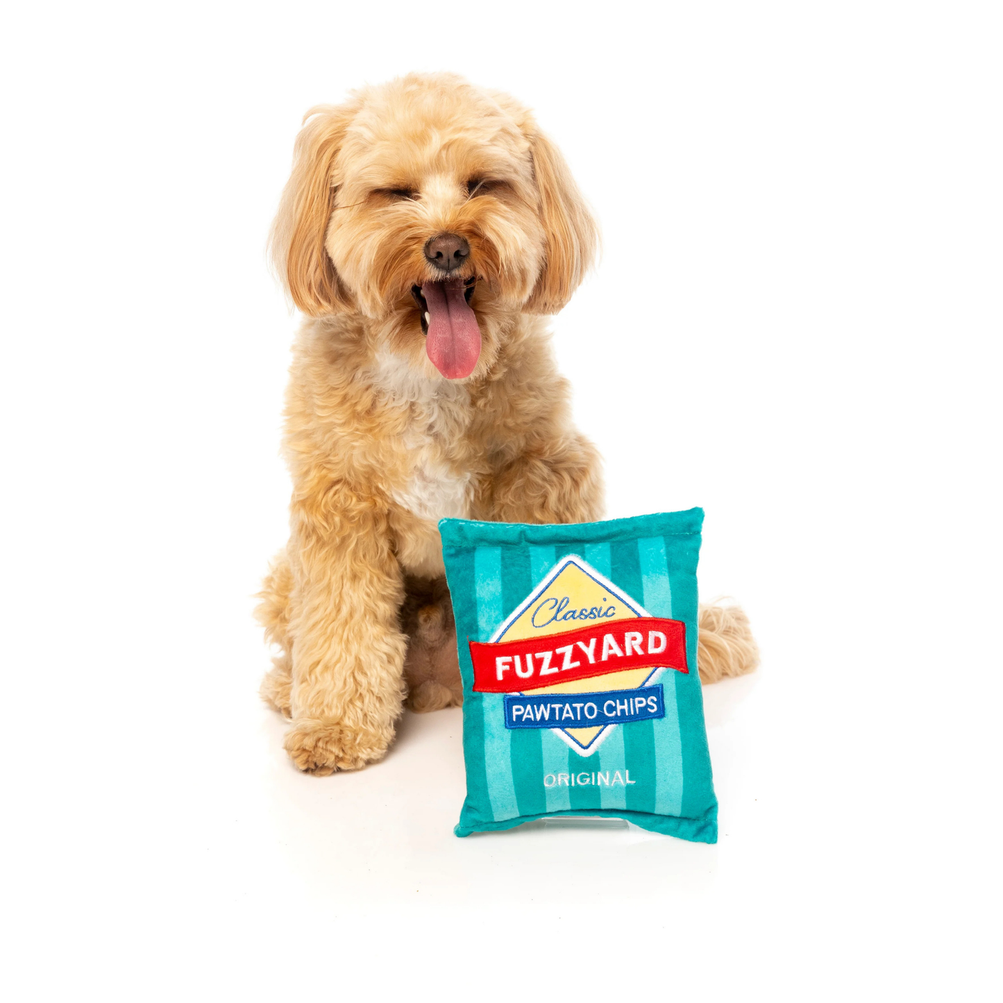Dog holding a Fuzzyard Pawtato Chips packet shaped toy on a white background