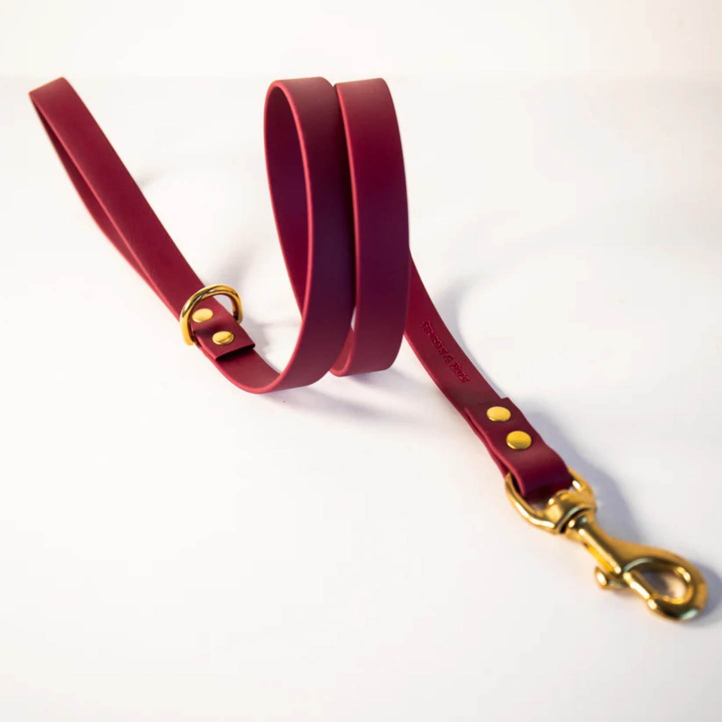 Wine colour dog lead with gold hardware on a white background